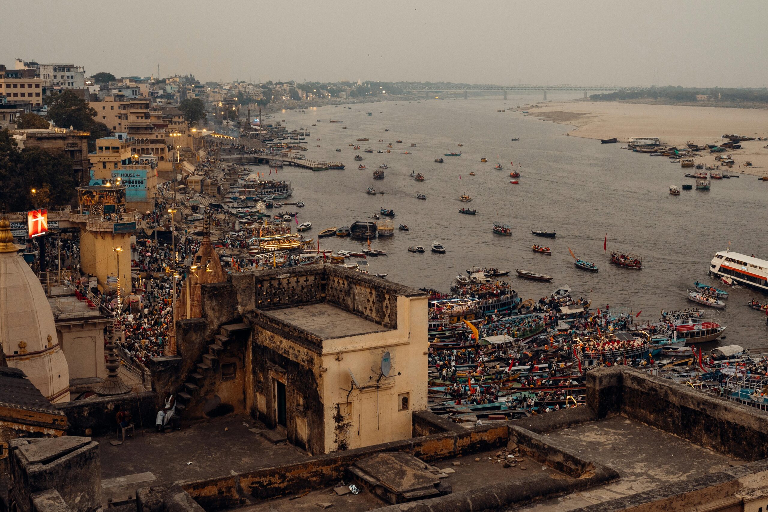 Vibrant Varanasi riverside scene featuring boats and ancient architecture along the Ganges at dusk.
