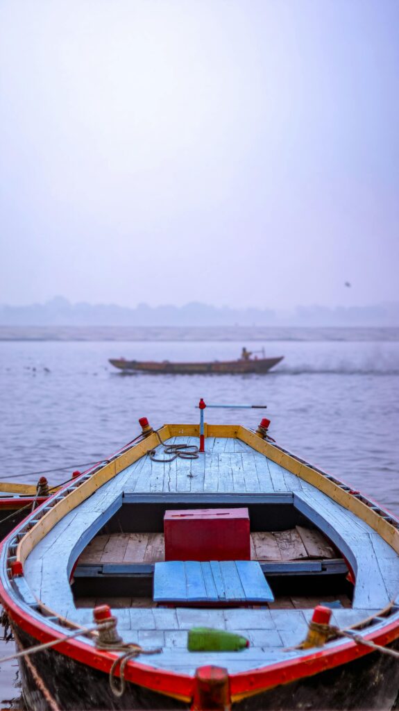A vibrant wooden boat floats on the Ganges River in Varanasi, capturing the serene beauty of India.