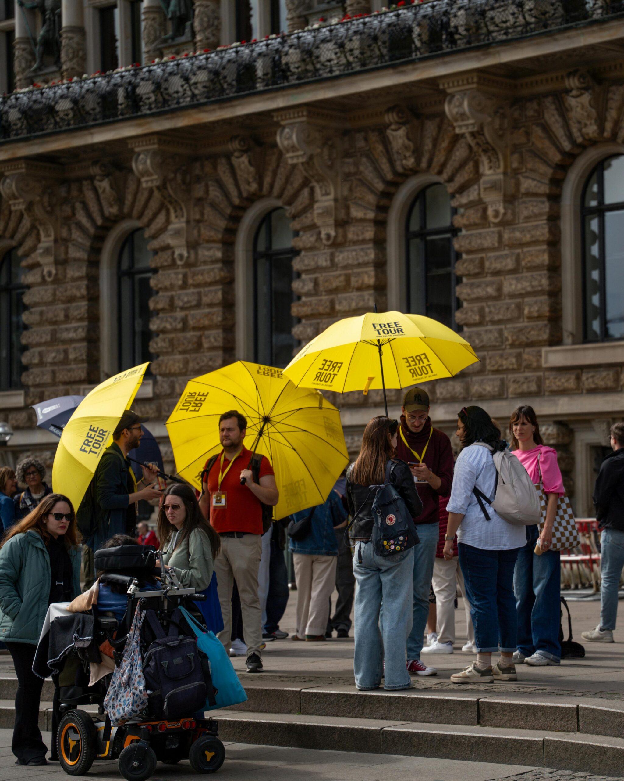 Group of tourists with yellow 'free tour' umbrellas in a city center.