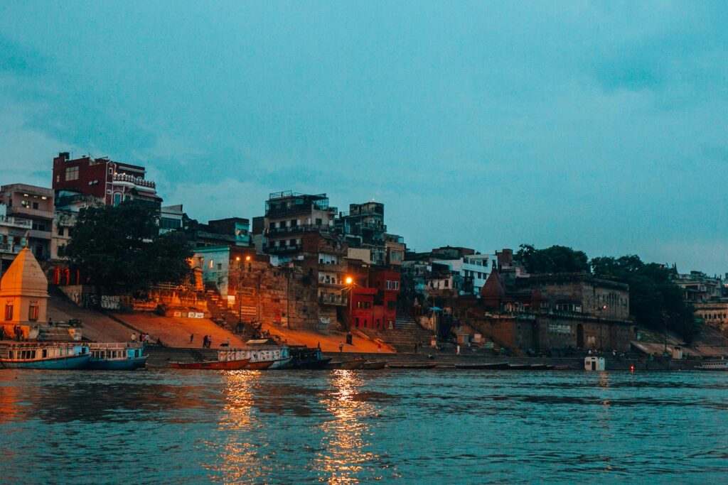 Scenic view of the illuminated Varanasi waterfront along the Ganges River at twilight.